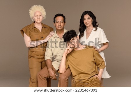 Portrait of a Black woman with albinism in her 20's, a Hispanic woman in her 50's, a non-binary Caucasian person in their 20's, and an Indian man in his 50's looking at the camera. Royalty-Free Stock Photo #2201467391