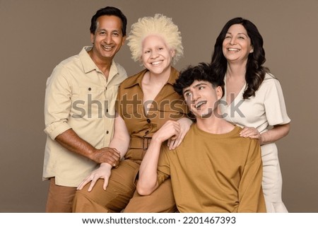 Portrait of a Black woman with albinism in her 20's, a Hispanic woman in her 50's, a non-binary Caucasian person in their 20's, and an Indian man in his 50's laughing together. Royalty-Free Stock Photo #2201467393