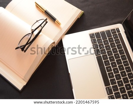 Black background with laptop, block-note, glasses hand watch and pen.
Work and study atmosphere in a calm place. 