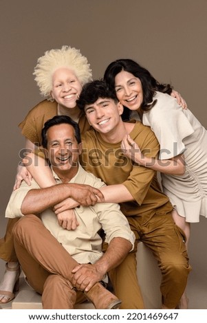 Studio shot a Black woman with albinism in her 20's, a Hispanic woman in her 50's, a non-binary caucasian person in their 20's, and an Indian man in his 50's smiling on a neutral background. Royalty-Free Stock Photo #2201469647
