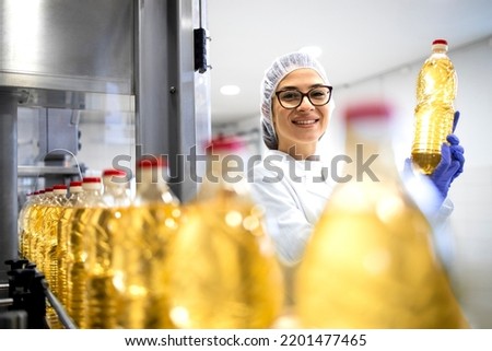 Portrait of female technologist inside food production factory and controlling quality of refined vegetable oil products. Royalty-Free Stock Photo #2201477465