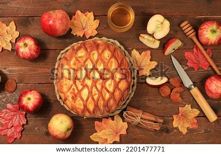 Kitchen autumn background with apple pie, honey, apples, spices and seasonal flowers and leaves, cozy warm concept, hello autumn, hygge style, modern bakery advertisement, selective focus, top view
