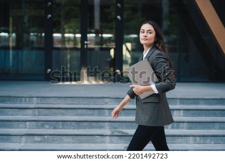 A brunette businesswoman walking in city street with laptop going to work in the morning. Copy space. Getting outside for a change. Businessman holding laptop Royalty-Free Stock Photo #2201492723
