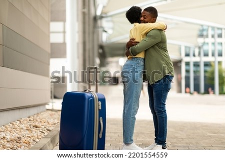 Black Husband Meeting His Wife In Airport, Hugging Expressing Love After Seperation Standing With Suitcase In Terminal Indoor. Transportation And Long Distance Relationship Concept Royalty-Free Stock Photo #2201554559