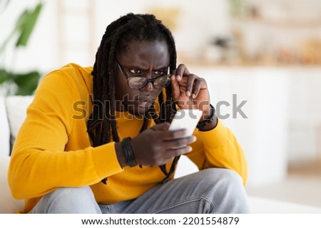 Bad Vision. Young Black Guy In Eyeglasses Looking At Smartphone Screen At Home, African American Man Trying To Read Message On Mobile Phone, Suffering Astigmatism Or Poor Eyesight, Closeup Royalty-Free Stock Photo #2201554879