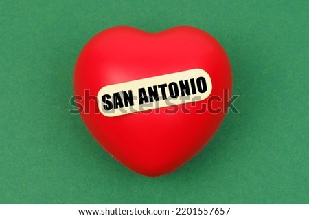 Love for the city, homeland. On a green surface lies a red heart with the inscription - San Antonio