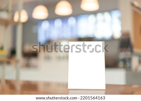 Menu frame with white blank screen on wooden table in restaurant or cafe on bokeh background.