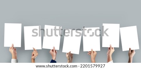 Many hands holding a blank a4 poster for advertising on grey background. Royalty-Free Stock Photo #2201579927