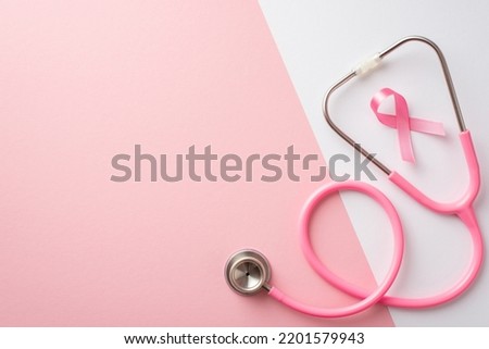 Breast cancer awareness concept. Top view photo of pink silk ribbon and stethoscope on bicolor pastel pink and white background with copyspace