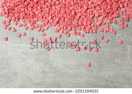 Pink heart shaped sprinkles on grey table, flat lay. Space for text Royalty-Free Stock Photo #2201584035
