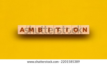 Ambition word written on wooden blocks with yellow background