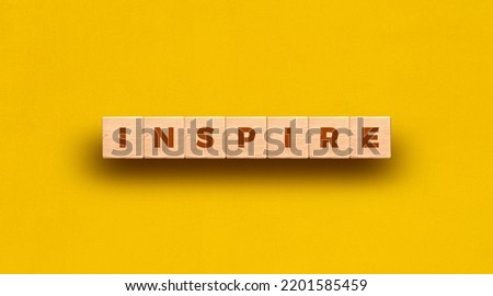 Inspire - word written on wooden blocks with yellow background