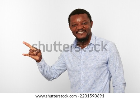 Happy african american black man with sign of horns gesture in casual bright shirt isolated on white background. Smiling adult black guy portrait with sign of horns, candid excited male emotion