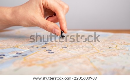 Woman hand pushing pin on map. Trip planning. Female marking travel destination, location with pushpin. Adventure, navigation, logistics concept. High quality photo Royalty-Free Stock Photo #2201600989