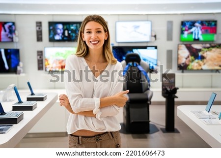 Beautiful young woman choosing which digital device to buy in tech store.. Royalty-Free Stock Photo #2201606473