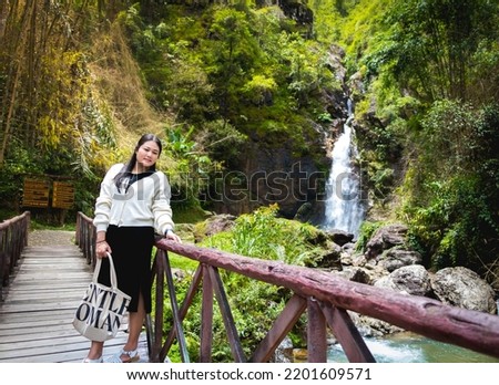 Asian woman standing enjoy with Jogkradin Waterfall background in Kanchanaburi , Thailand Green ozone ecology, natural therapy, Eco Friendly, eco earth day concept