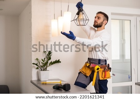 Electrician installs lamp lighting and spot loft style on ceiling. Royalty-Free Stock Photo #2201621341