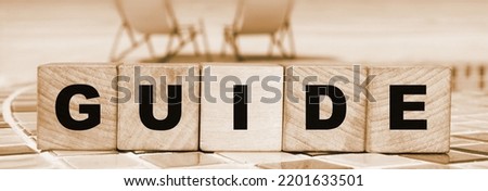 Guide Word Written In Wooden Cubes on relaxed beach landscape background. Travel concept.
