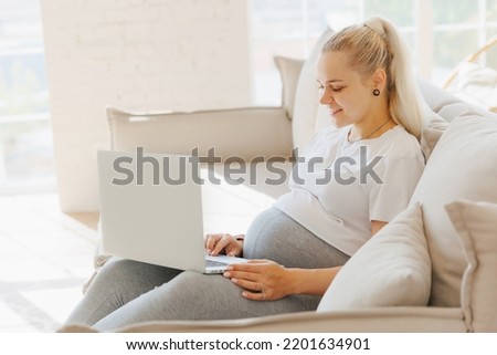 Portrait young pregnancy woman using online laptop on sofa with sunlight.