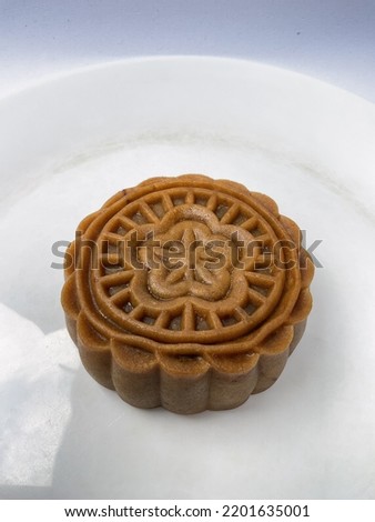 This is a traditional mid autumn snack. Food photography, Closeup picture of a baked moon cake on a white plate.