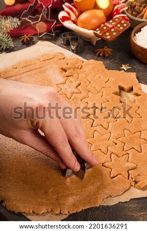  Hand is cuting out traditional homemade Christmas gingerbread cookie dough close-up, vertical photo. Baking for Christmas. High quality photo