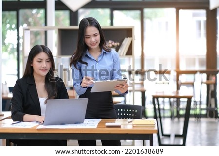 Two Young Asian businesswoman discuss with new startup project Idea presentation, analyze planning and financial statistics and investment market at office.
