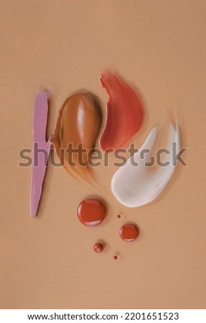 Cosmetics for makeup smears textures composition. On an orange color background, top view.