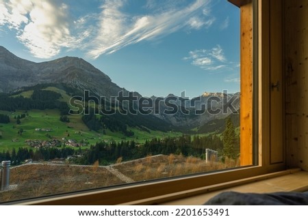 beautiful morning view through the great wooden window to the mountains from Adelboden, Switzerland. Dawn and alpenglow on the mountain peaks with glacier. the twilight in the valley is getting bright