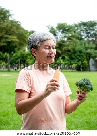 Portrait of happy senior adult elderly asia woman smiling standing and holding fresh vegetable in the park.