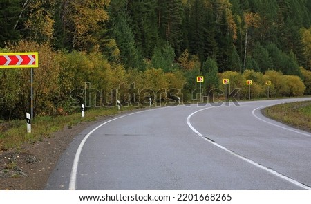 sharp turn road highway in the autumn forest turn signs