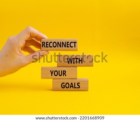 Reconnect with your Goals symbol. Wooden blocks with words Reconnect with your goals. Beautiful yellow background. Businessman hand. Business and Reconnect with your goals concept. Copy space.