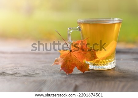 Autumn still life with a teacup with a slice of lemon on wooden boards and a blurred background in the background with a place to copy. Selective focus