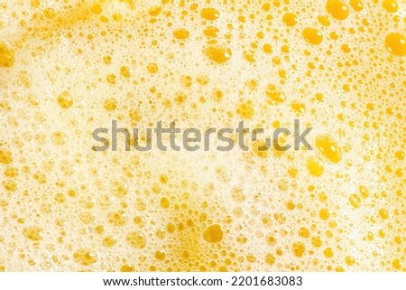Closeup of orange juice foam, top view. Splash of fresh sweet orange, mango, fruit juice. Freeze motion of pouring orange juice .
