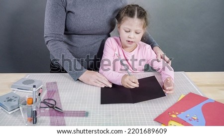 Little girl making a handmade Father's Day card from construction paper.