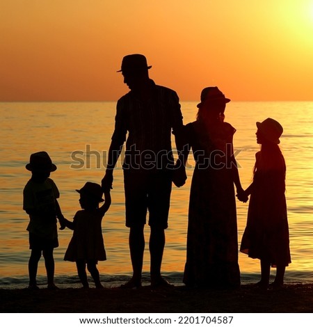 family silhouette at sunset by the sea in summer