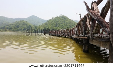 A wooden bridge spans the reservoir. with mountains in the background