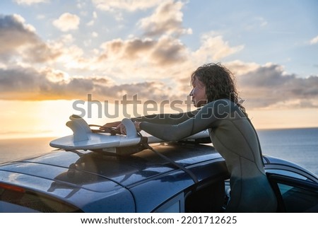 Curly young woman taking surfboard from her car and preparing for the training Royalty-Free Stock Photo #2201712625