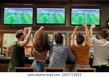 Cheering friends of soccer fans in the pub  Royalty-Free Stock Photo #2201712823