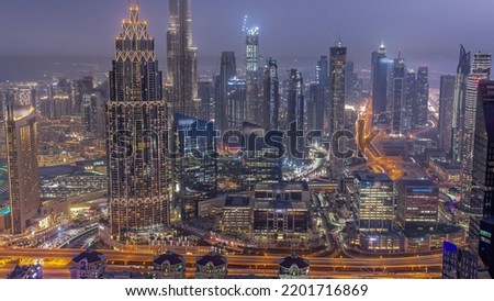 Aerial view of tallest towers in Dubai Downtown skyline and highway day to night transition timelapse. Skyscraper and high-rise buildings under construction