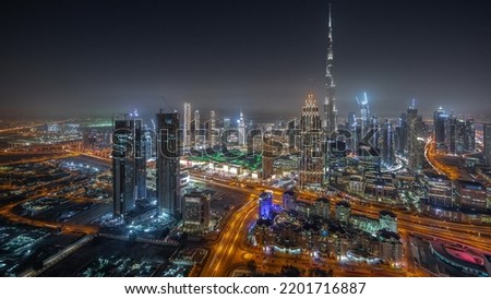 Aerial view of tallest towers in Dubai Downtown skyline and highway night timelapse. Financial district and business bay with creek area in smart urban city. Skyscraper and high-rise buildings