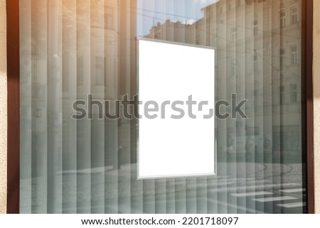 Vertical white poster hanging behind window case of store or fashion outlet in sale season