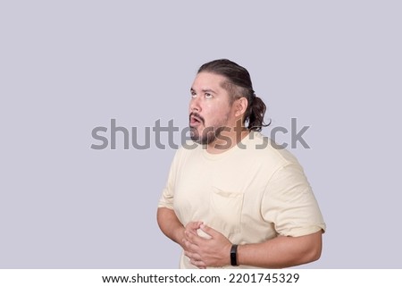 A man in his 30s experiences uncomfortable abdominal cramping, stomachache, or just belching. Royalty-Free Stock Photo #2201745329
