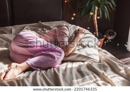 Depressed middle-aged alone female curled up in fetal position lying in bed, concept of chronic insomnia, sleeping disorder, grieving about divorce or diagnosis disease, mental problems Royalty-Free Stock Photo #2201746335