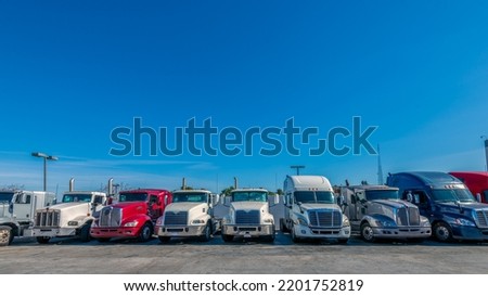 Lined up Semi trucks on a parking lot at logistics warehouse Royalty-Free Stock Photo #2201752819
