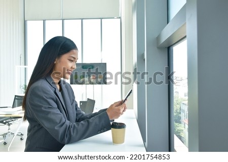 happy  busimess Asian woman drinking hot coffee and used mobile phone with relaxing time in office