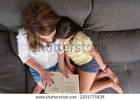 Top view of a Happy mother and child sitting on the couch and reading a book. High quality photography.