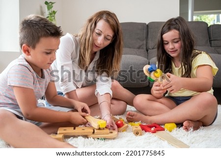 Single mother playing with her kids at home. High quality photography.