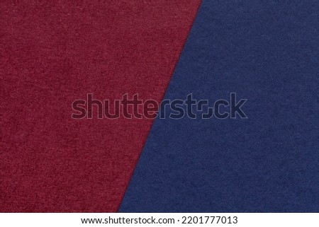 Texture of craft navy blue and dark red paper background, half two colors, macro. Structure of vintage dense kraft wine cardboard. Felt backdrop closeup.