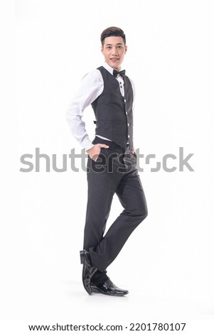 Full length portrait of a businessman in black vest with white shirt , with bow tie standing on white background