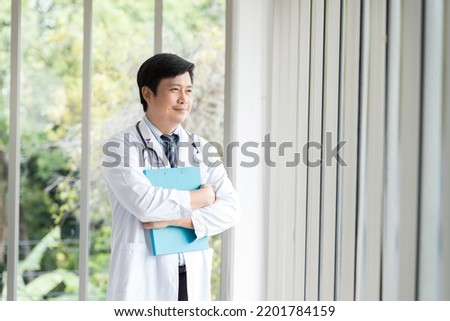 Happy asian male doctor wear uniform with stethoscope standing at the hospital